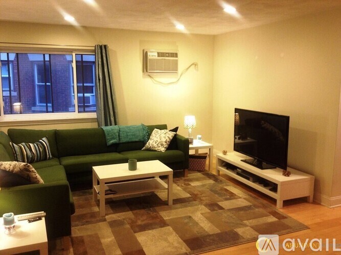 A living room with a green couch, a white coffee table, and a flat screen TV.