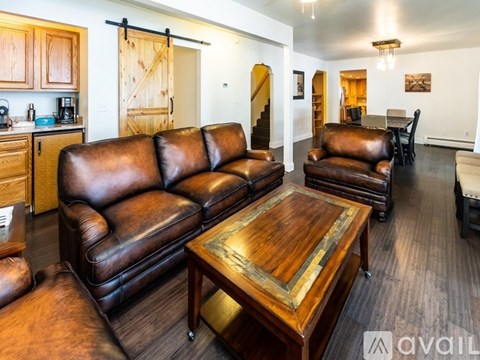 A living room with brown leather furniture and a wooden coffee table.