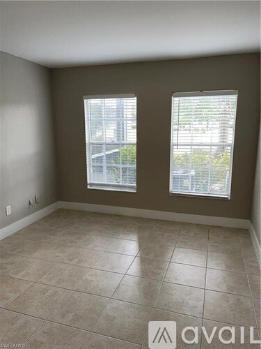 A room with two windows and tiled flooring.