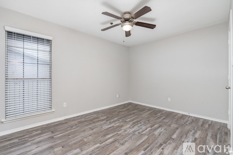 A room with a ceiling fan and wooden flooring.