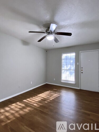A room with a ceiling fan and wooden flooring.