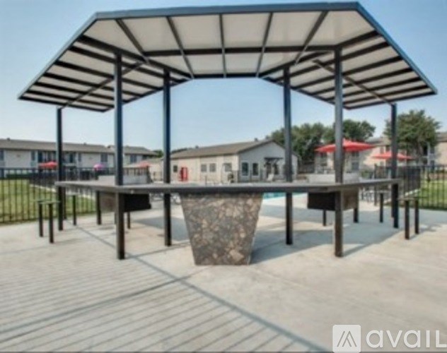 A covered outdoor seating area with a stone planter in the center.