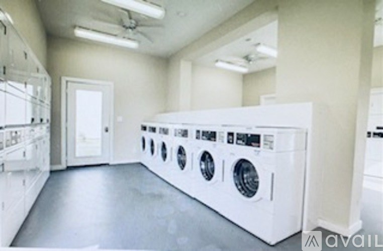 A row of white front loading washing machines in a laundry room.