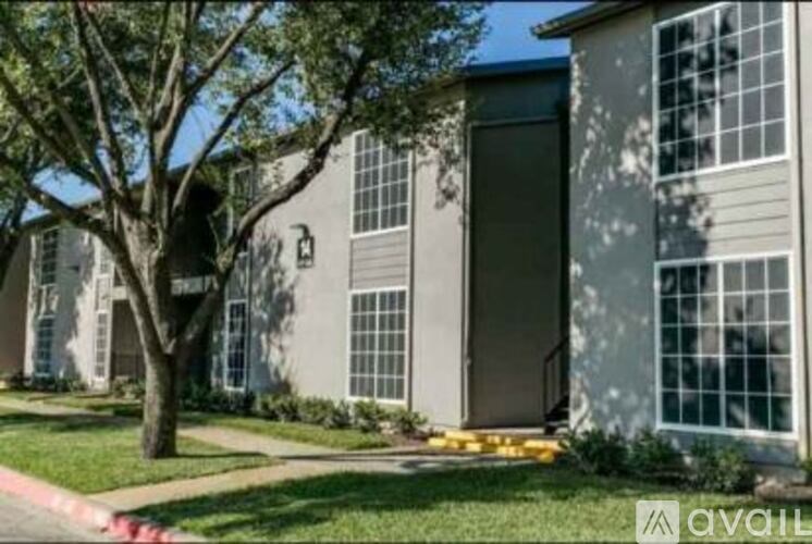 A tree is in front of a grey building.