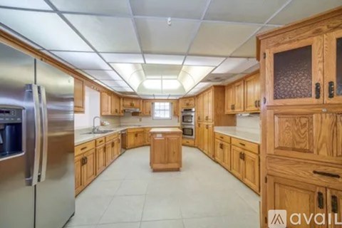 A kitchen with wooden cabinets and a stainless steel refrigerator.