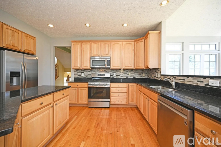 A kitchen with wooden cabinets and black countertops.