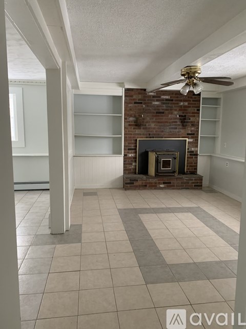 A living room with a fireplace and a ceiling fan.