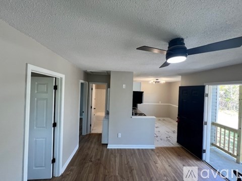 A room with a ceiling fan and a door on the left side.