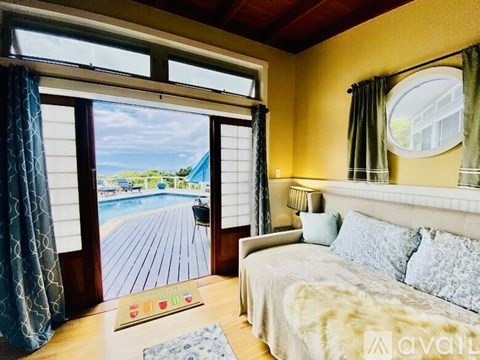 A bedroom with a large bed and a view of a deck outside through the window.