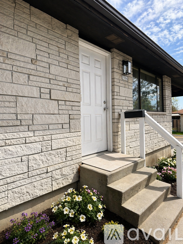 A white picket fence surrounds a house with a stone chimney.