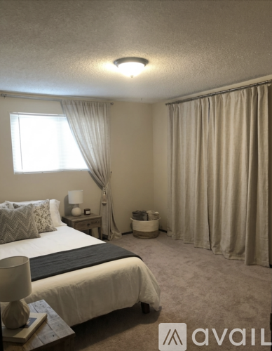 A bedroom with a bed, nightstand, and window with curtains.