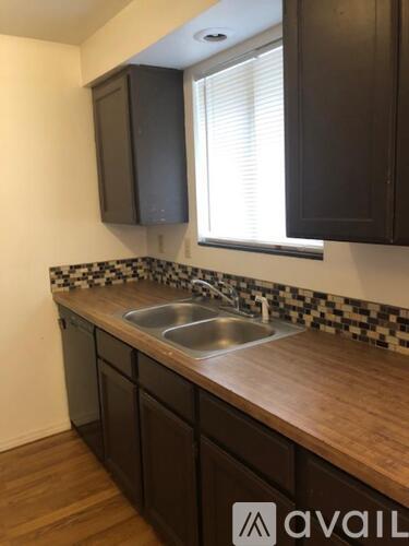 A kitchen with dark brown cabinets and a checkered backsplash.