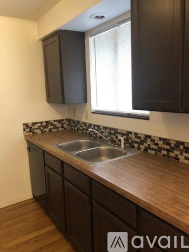 A kitchen with dark brown cabinets and a checkered backsplash.