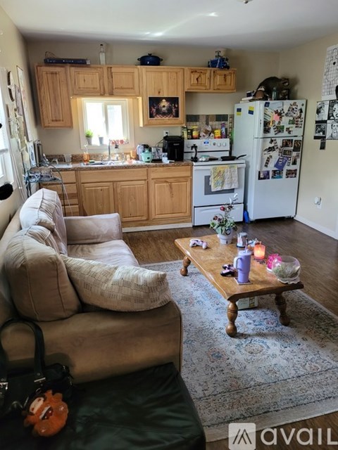 A living room with a couch, a coffee table, and a kitchen area in the background.