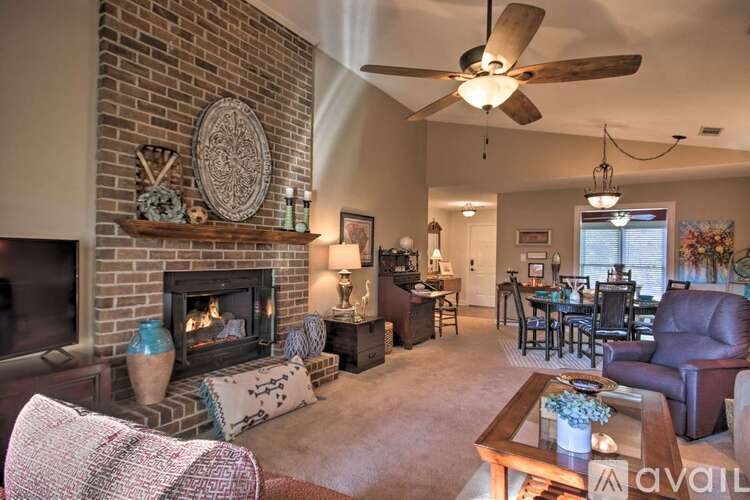 A living room with a brick fireplace and a ceiling fan.