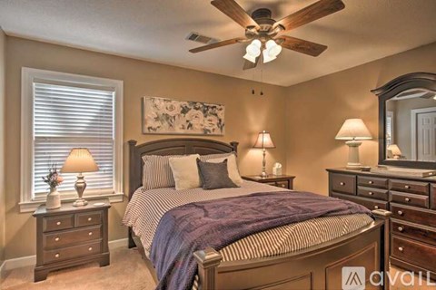 A bedroom with a bed, dressers, and lamps.