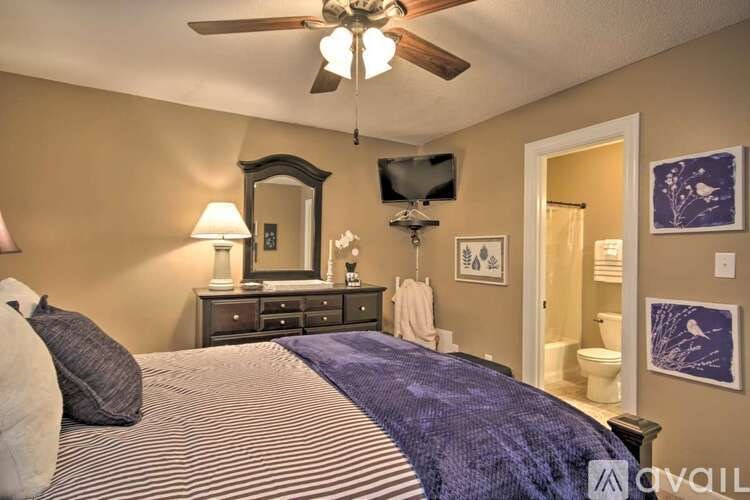 A bedroom with a bed, dresser, mirror, and ceiling fan.