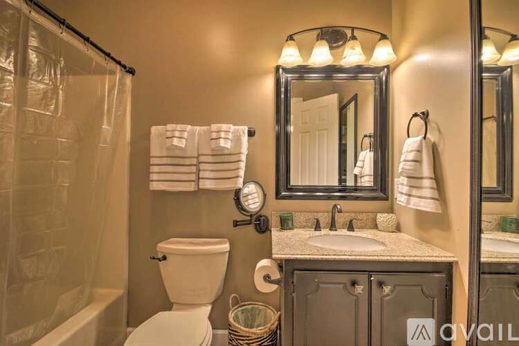 A bathroom with a toilet, sink, and mirror.