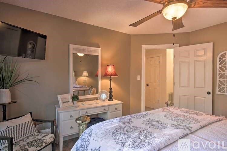A bedroom with a bed, desk, chair, and a ceiling fan.