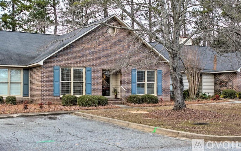 A brick house with blue shutters and a tree in front.