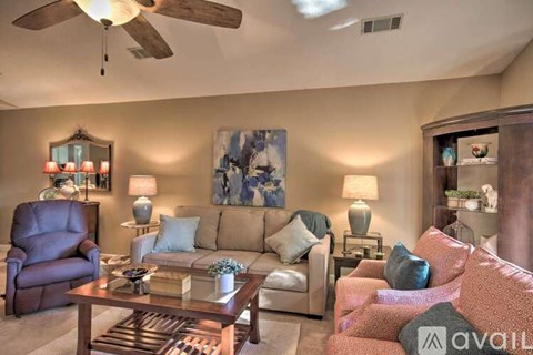A living room with a brown leather chair, a glass coffee table, and a painting on the wall.