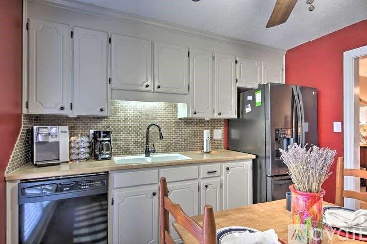 A kitchen with white cabinets and a black refrigerator.