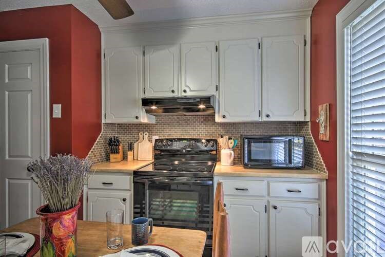 A kitchen with red walls and white cabinets.