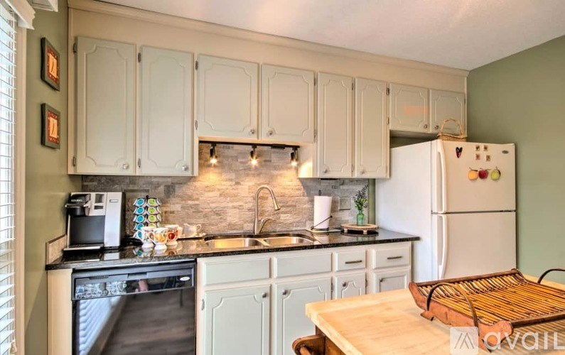 A kitchen with white cabinets and a white fridge.
