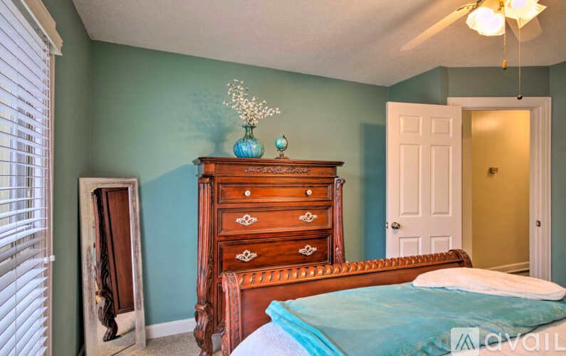 A bedroom with a bed, dresser, and a chandelier.