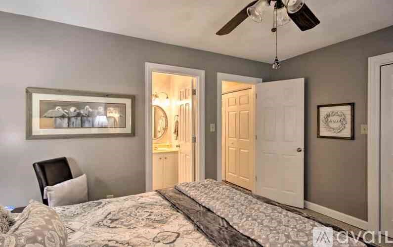 A bedroom with a bed, chair, and a ceiling fan.