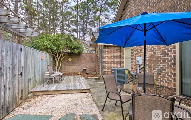 A blue umbrella is on a patio with a table and chairs.