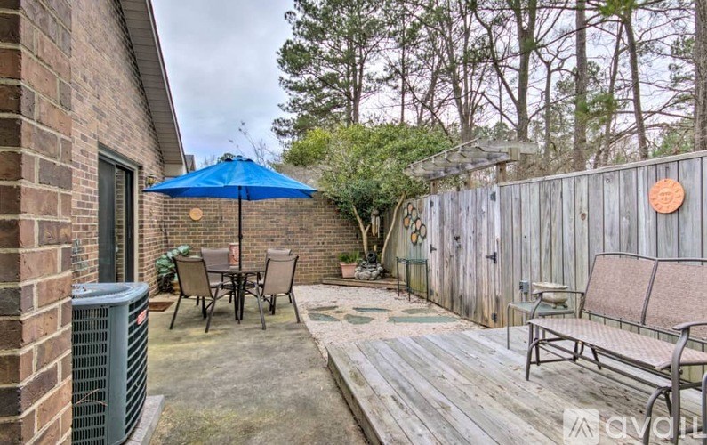 A patio with a blue umbrella and chairs.