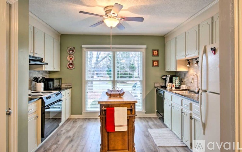 A kitchen with a white refrigerator, wooden island, and a ceiling fan.