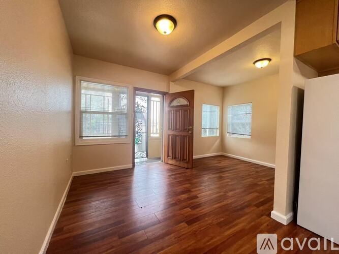 A room with wooden floors and a door leading to a balcony.