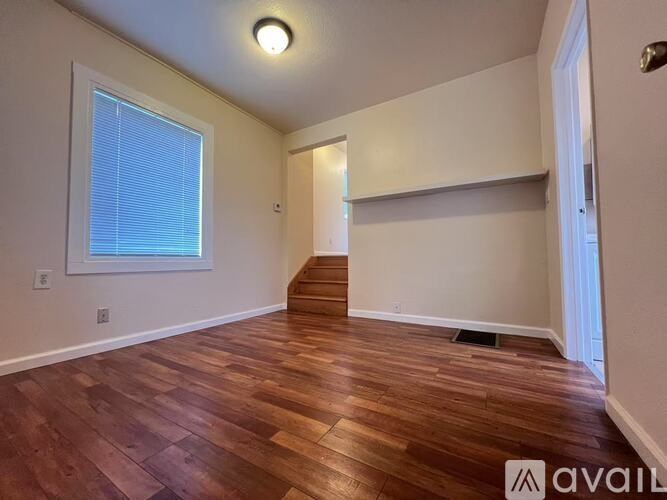 A room with wooden flooring and a window with blinds.