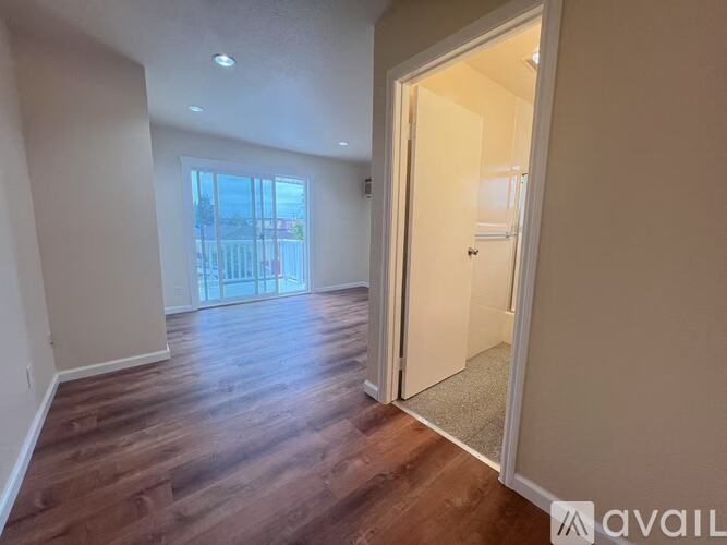 A room with wooden flooring and a door leading to another room.