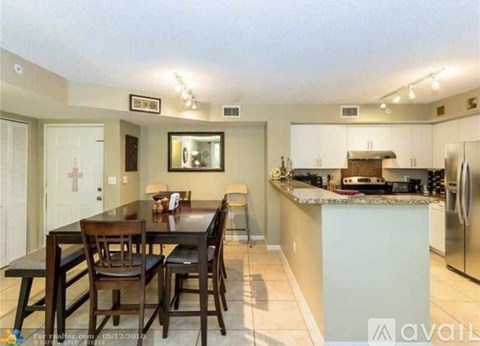 A kitchen with a table and chairs in the foreground and a refrigerator in the background.