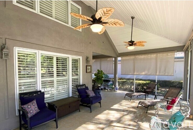 A patio with a ceiling fan and chairs.