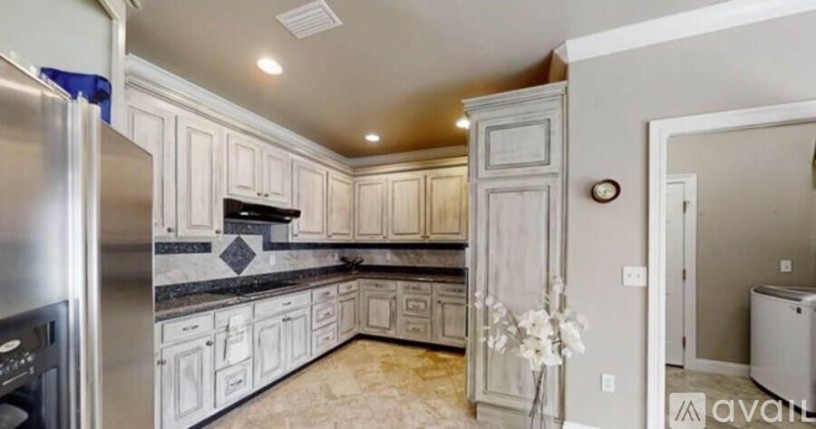 A kitchen with white cabinets and a marble floor.