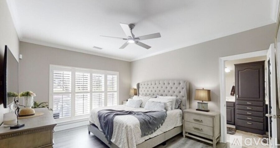 A bedroom with a bed, nightstand, and a ceiling fan.