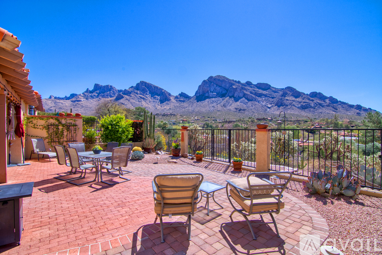 A patio with chairs and a table overlooking a mountain.