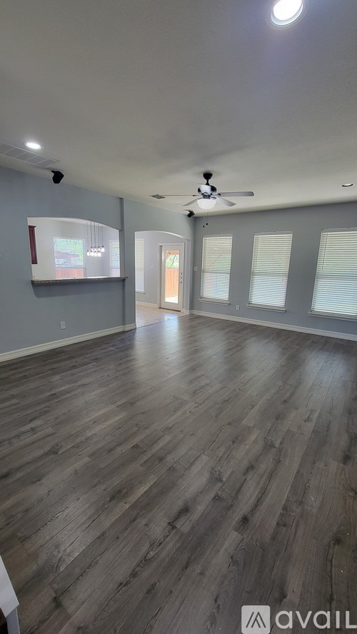 A spacious room with wooden flooring and a ceiling fan.