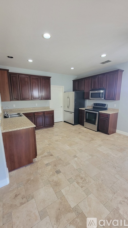 A kitchen with brown cabinets and a tiled floor.