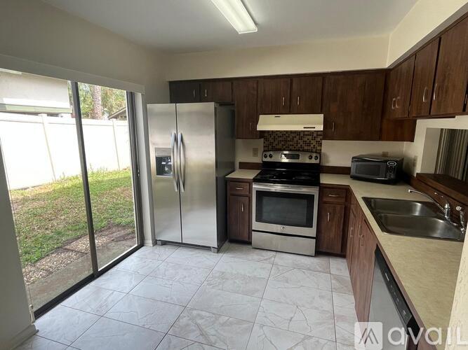 A kitchen with a refrigerator, oven, microwave, sink and cabinets.