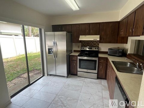 A kitchen with a refrigerator, oven, microwave, sink and cabinets.