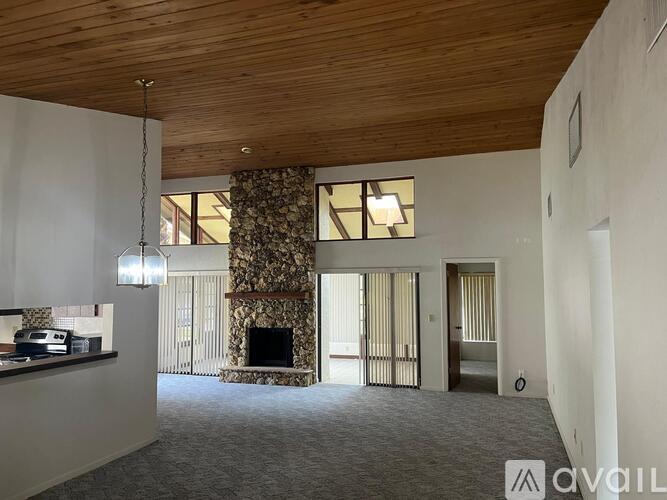 A living room with a fireplace and a wooden ceiling.