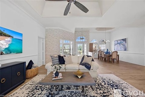 A living room with a white couch and a television showing a beach scene.