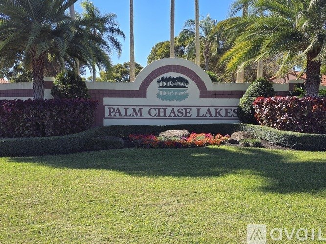 A sign that says Palm Chase Lakes in front of some trees.
