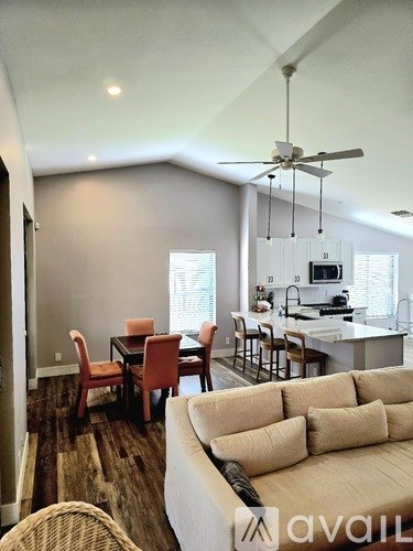 A living room with a couch, chairs, and a dining table.