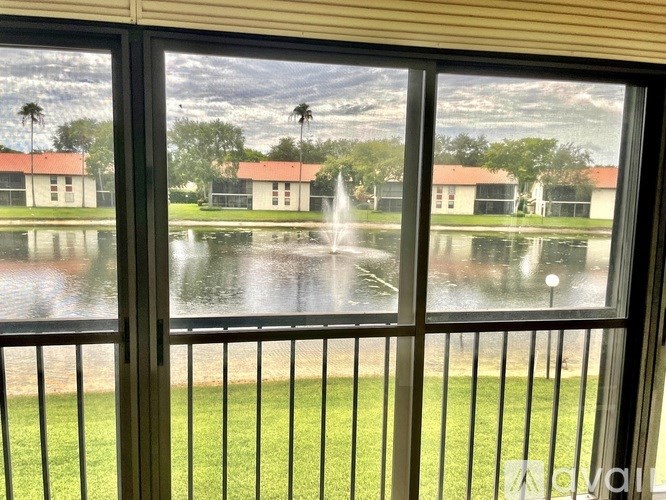 A view from a window looking out at a fountain and houses.
